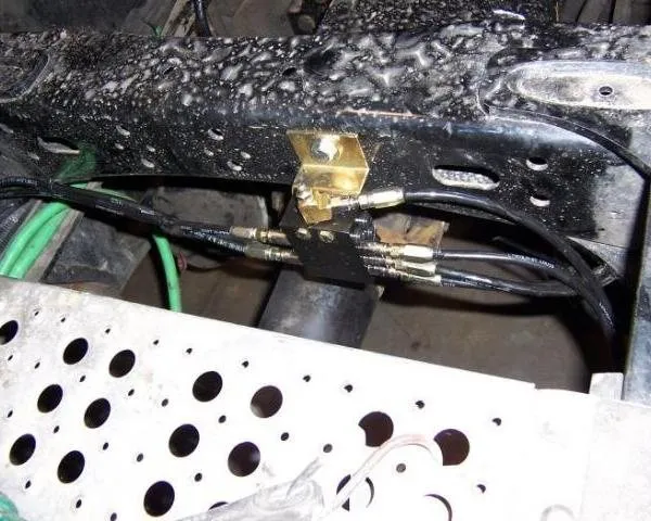 A brass grease divider block with several hose lines mounted under a truck-trailer frame rail