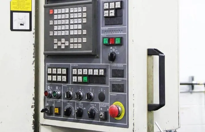 Close-up of a CNC machine's control panel with keypad and emergency stop button