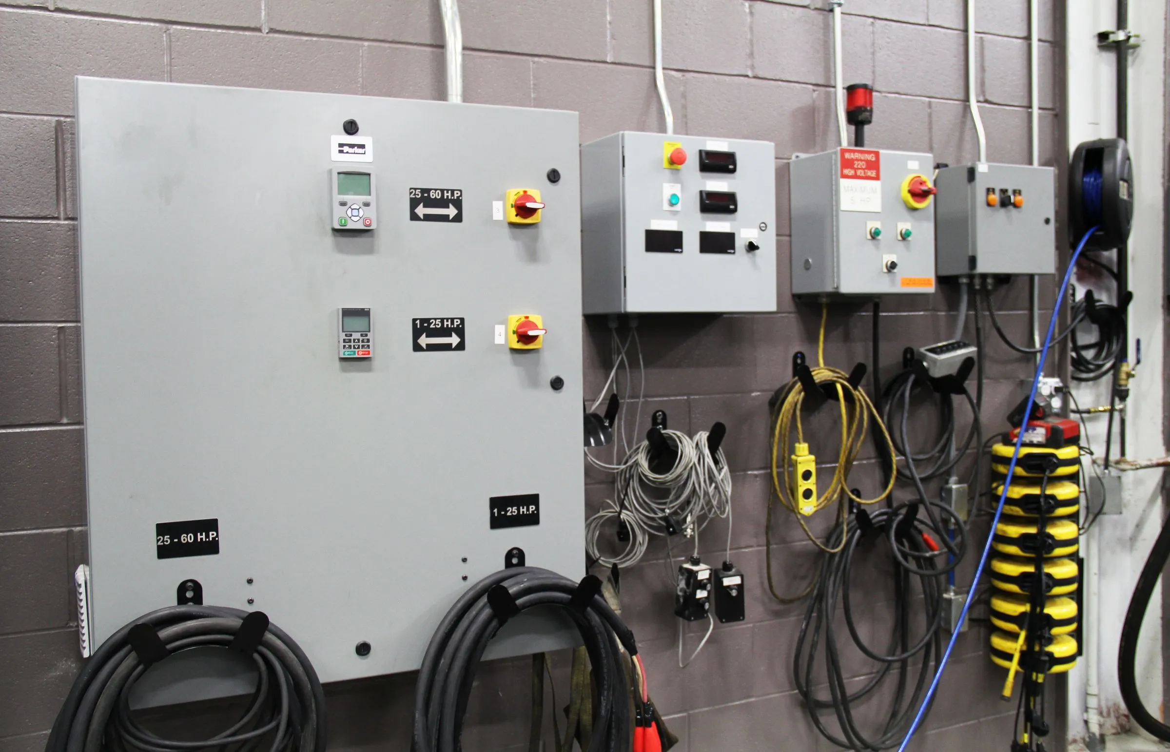 Row of gray control panels with horsepower-rated drives and hanging pendant controls