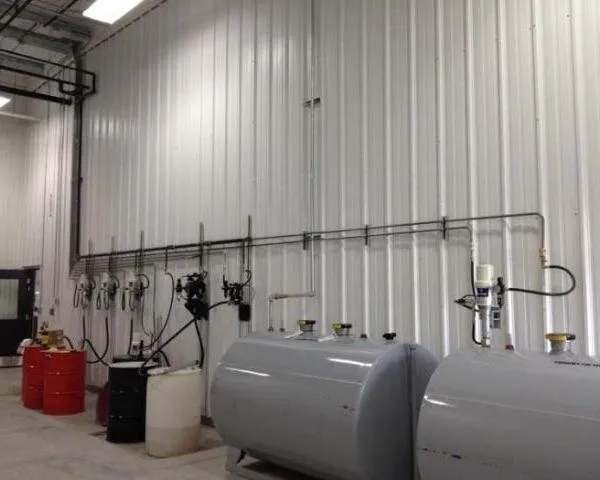 A fluid management wall with metered dispensing pumps and hose reels, next to large storage tanks
