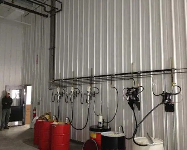 A fluid management wall with metered dispensing pumps and hose reels, with a worker near the doorway