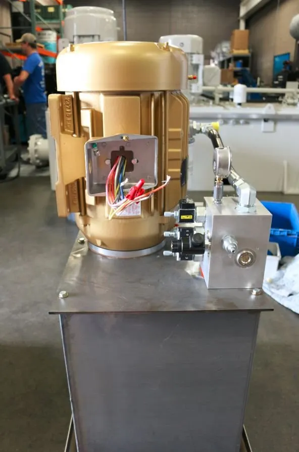 Gold-painted motor on a hydraulic reservoir with its electrical junction box open and wires exposed