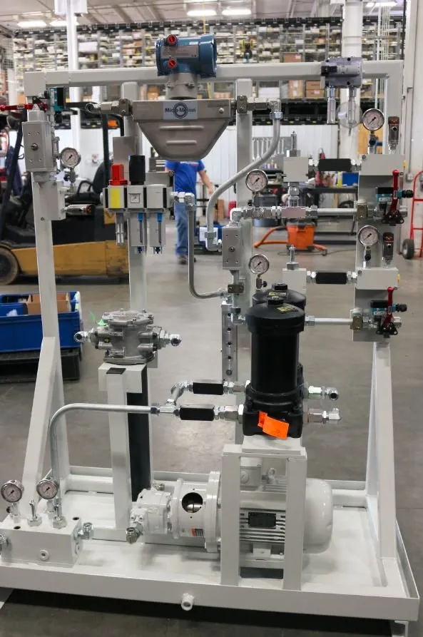 Hydraulic power unit skid with gauges, a black filter canister and a worker blurred in the background