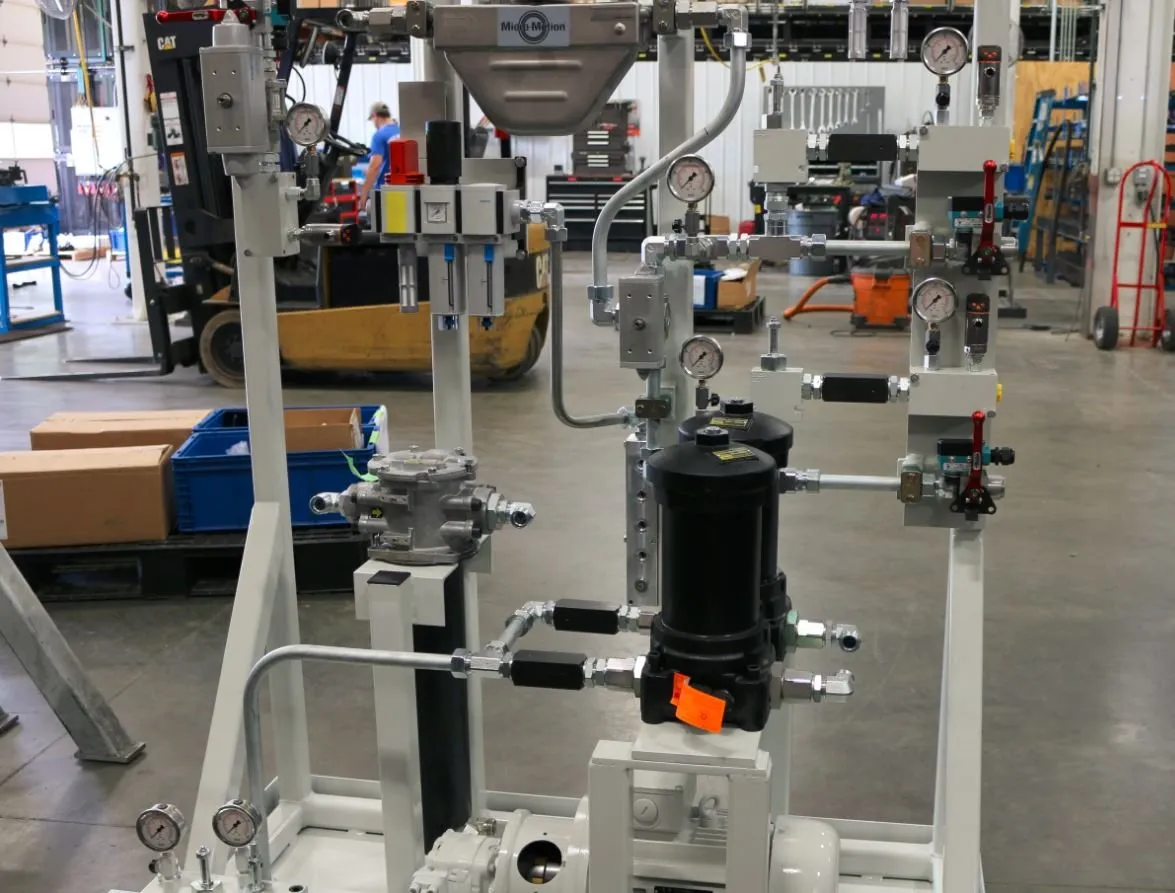 Hydraulic power unit skid with a Micro-Motion flow meter, filters and gauges, with a forklift and worker in the background