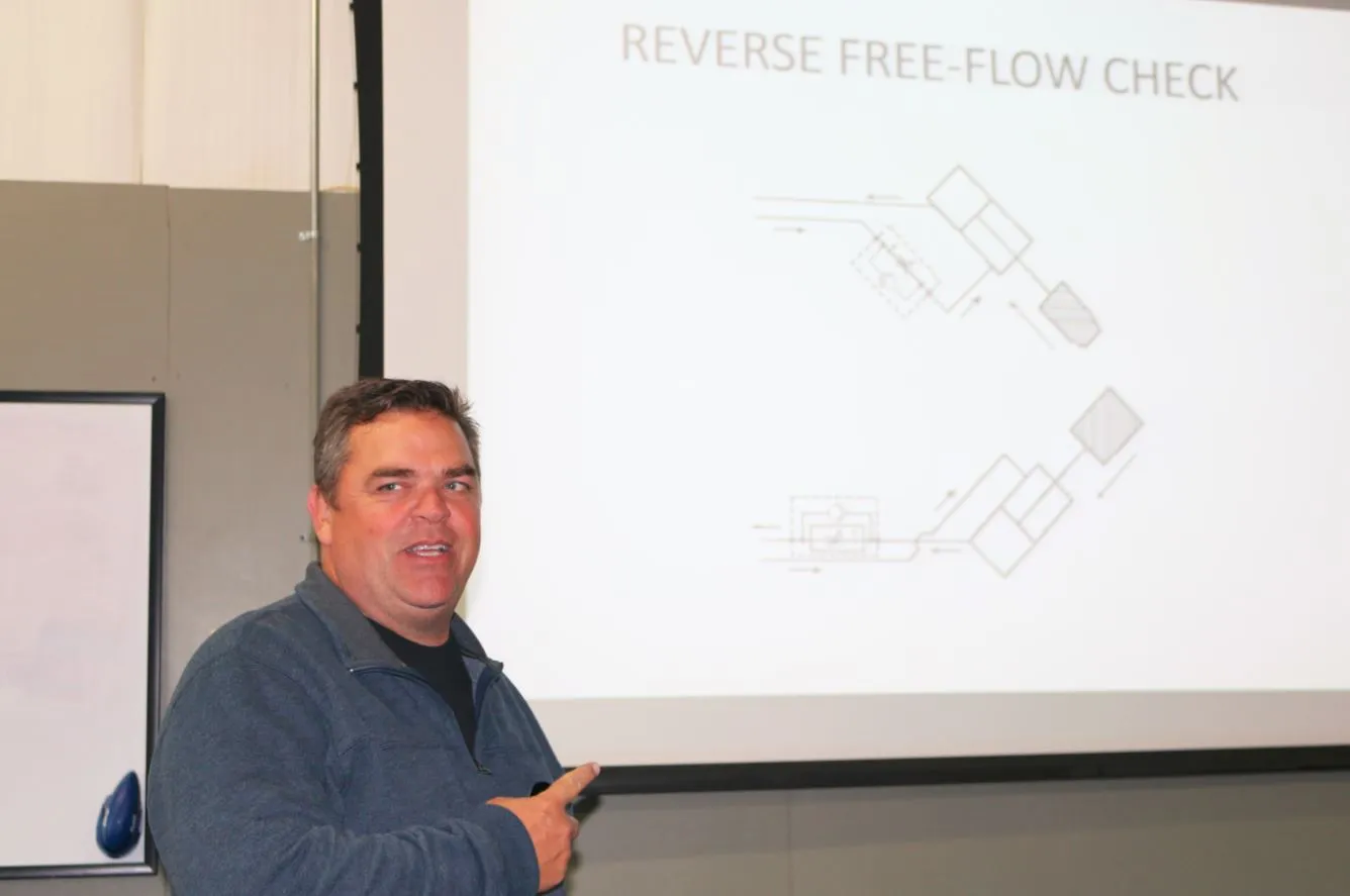 Instructor presenting a reverse free-flow check valve circuit on a projector screen