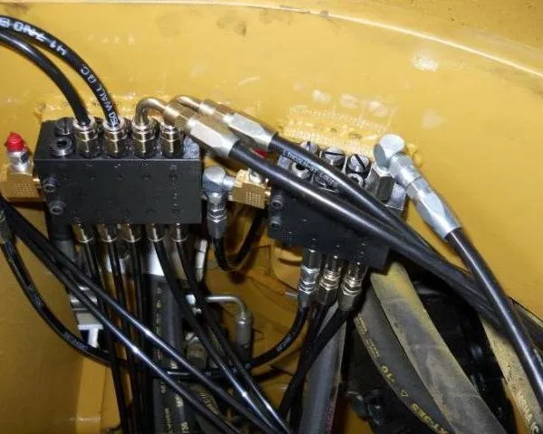 Automatic lubrication manifold with grease lines mounted on the yellow body of a haul truck