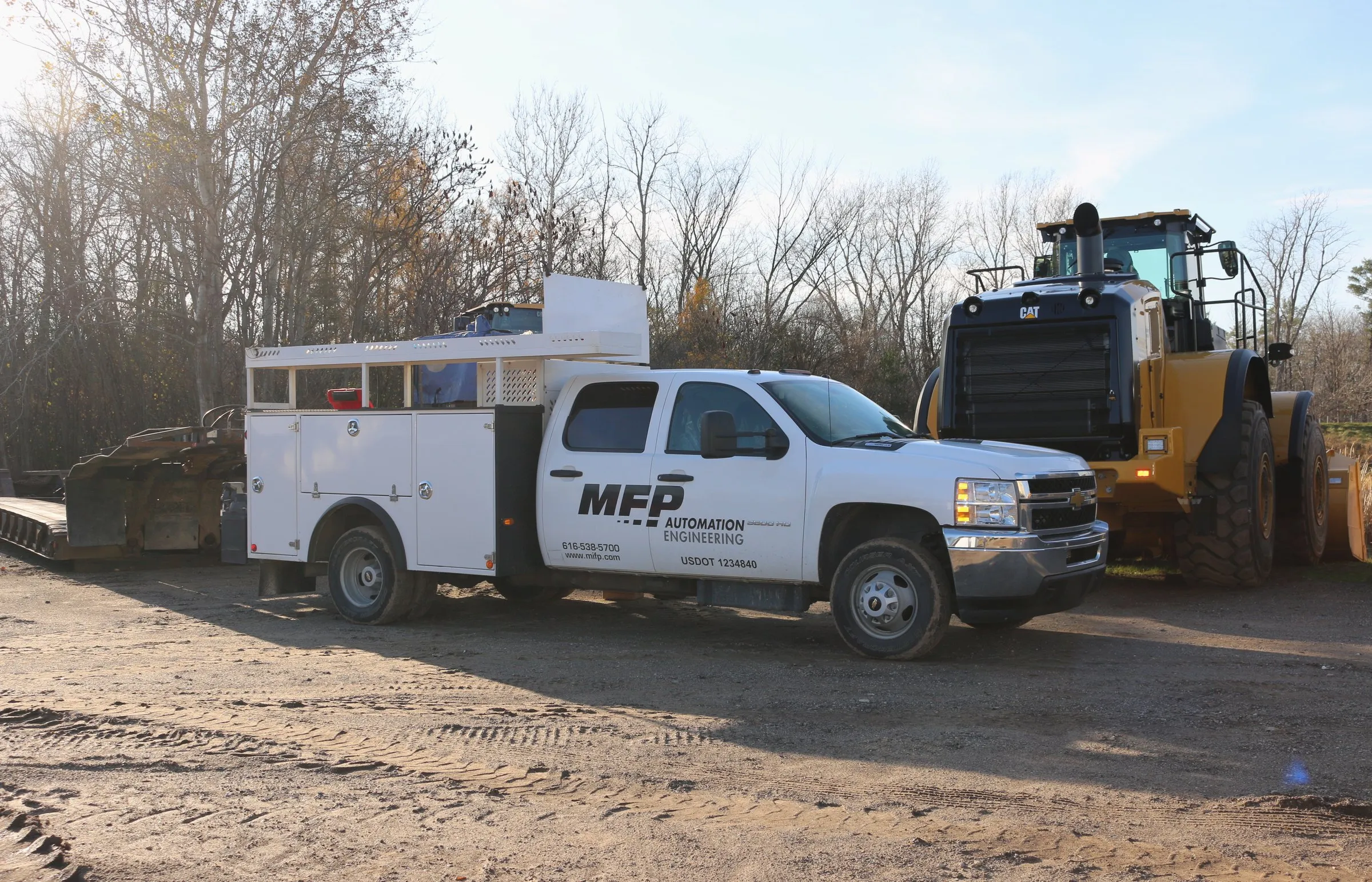 White MFP Automation Engineering truck parked beside a yellow Caterpillar wheel loader
