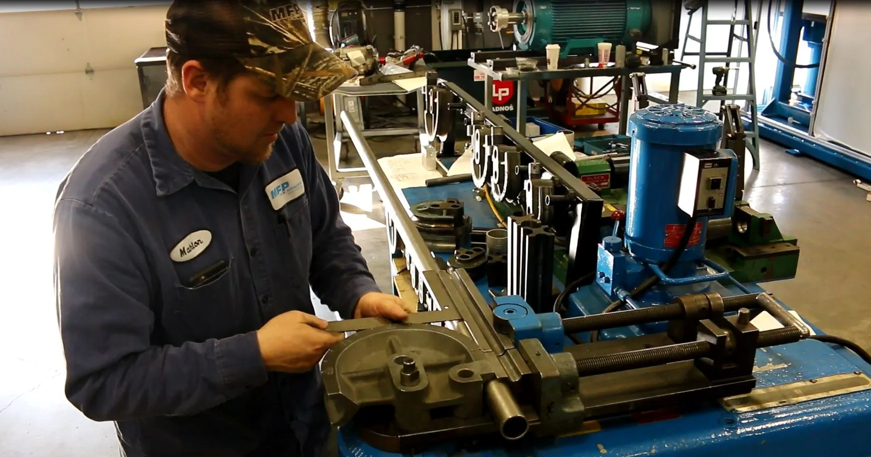 MFP technician setting up a steel tube in a hydraulic tube-bending machine in the shop