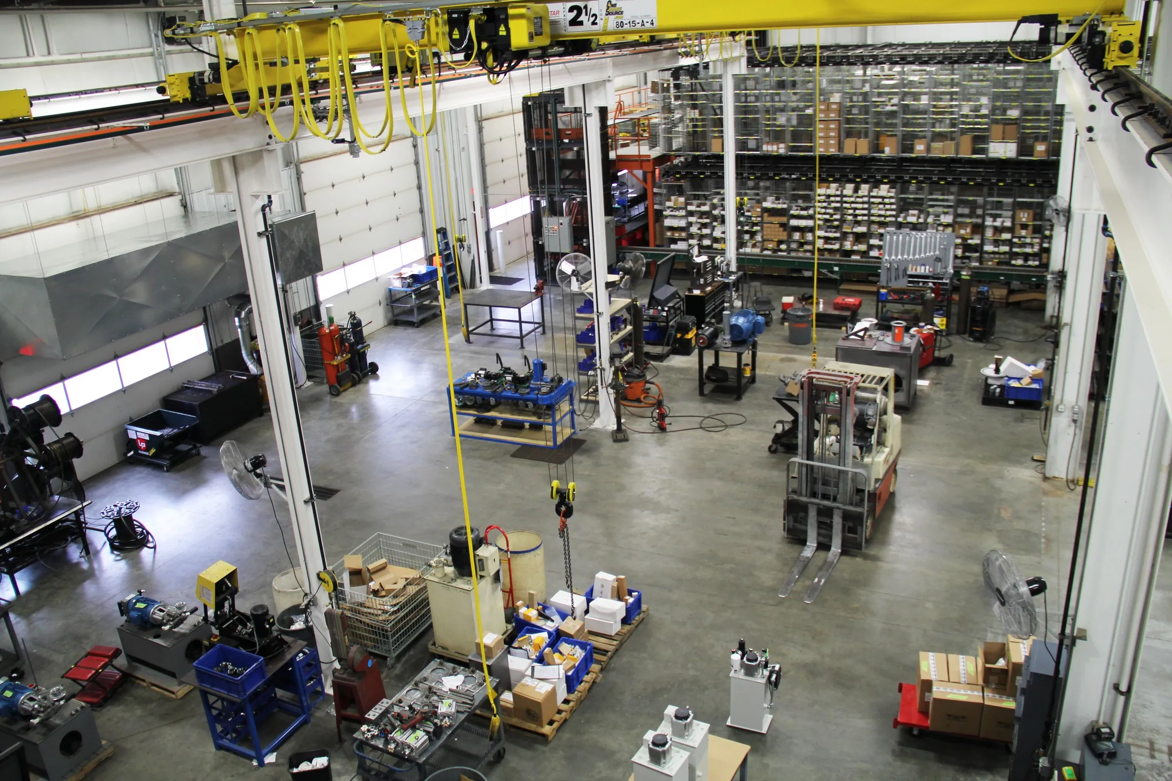 Overhead view of the shop floor at MFP in Hudsonville, MI: yellow bridge cranes, assembly areas and parts racks