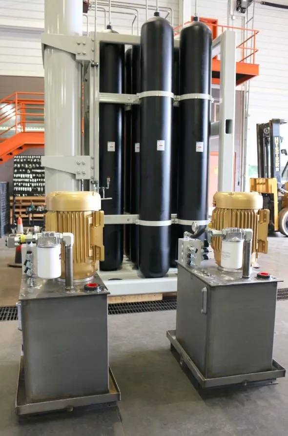 Two stainless steel hydraulic power units with gold motors, seen from another angle by the accumulator tanks