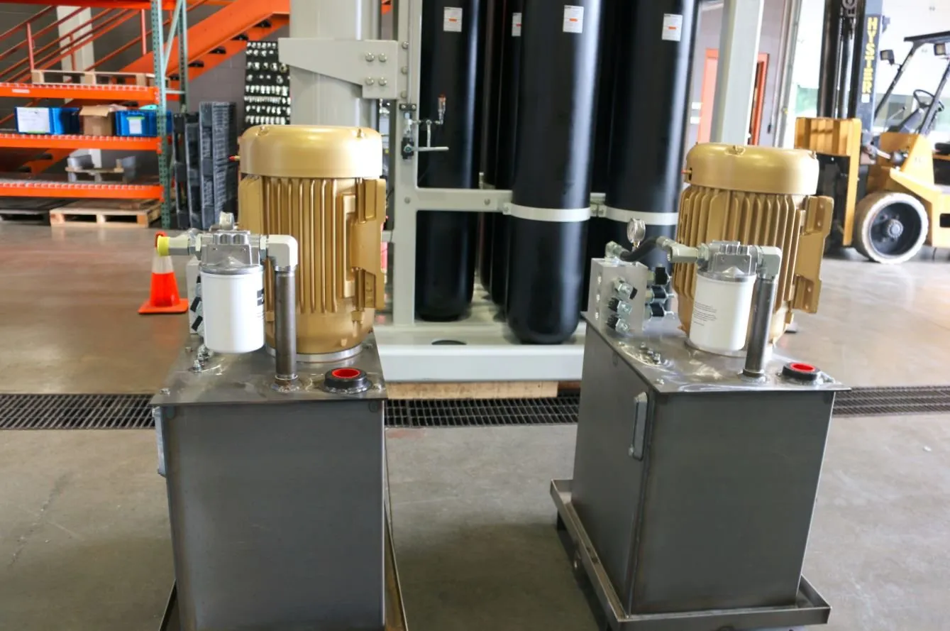 Two stainless steel hydraulic power units with gold motors, viewed close up in front of black accumulator tanks