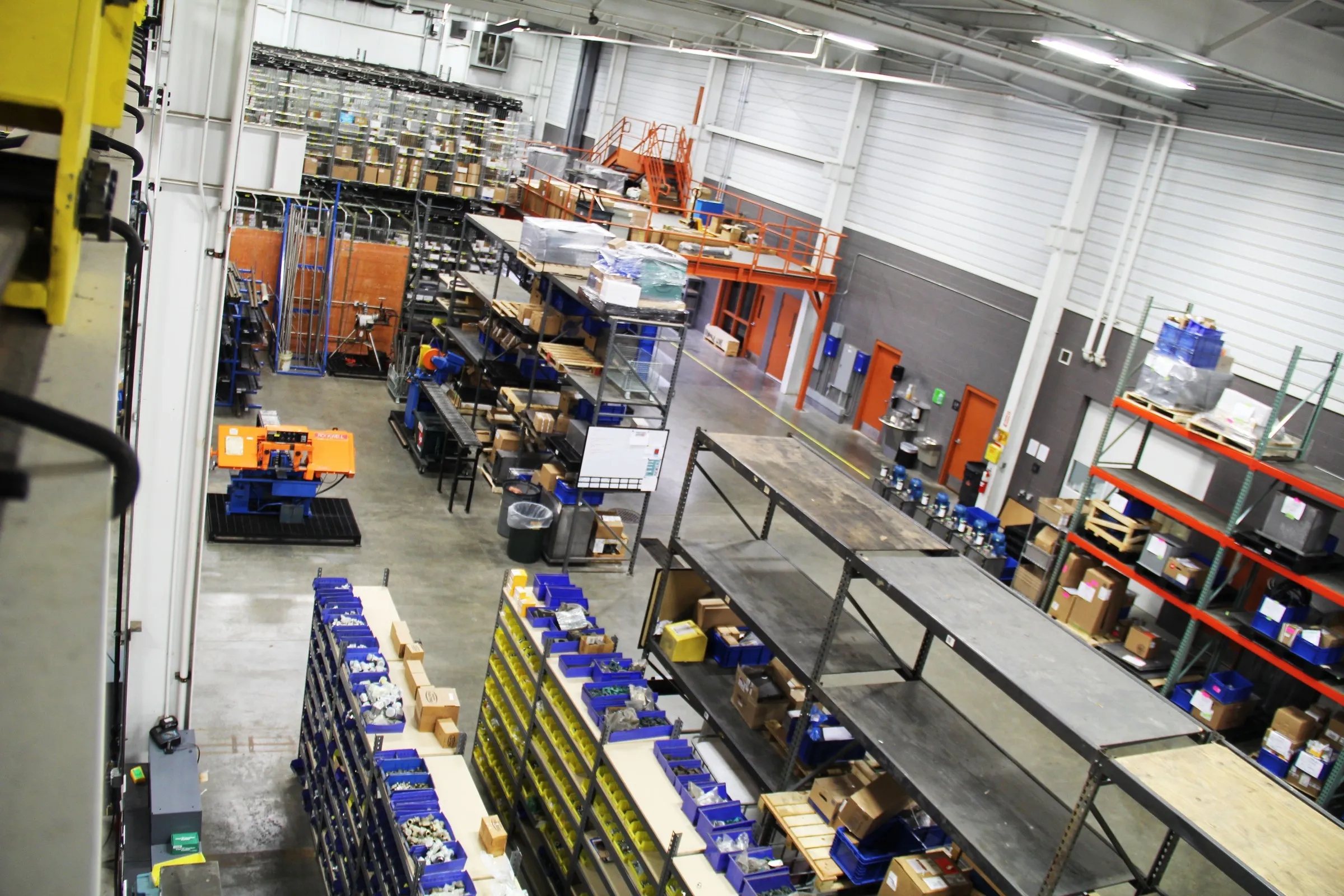 Overhead view of warehouse aisles with blue parts bins, orange racks and packing tables at MFP in Hudsonville, MI